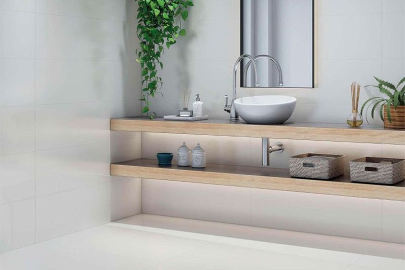 Azulejo 20 x 60 blanco brillo mono Halcón Cerámicas, instalado en paredes de baño con lavamanos y repisas de madera