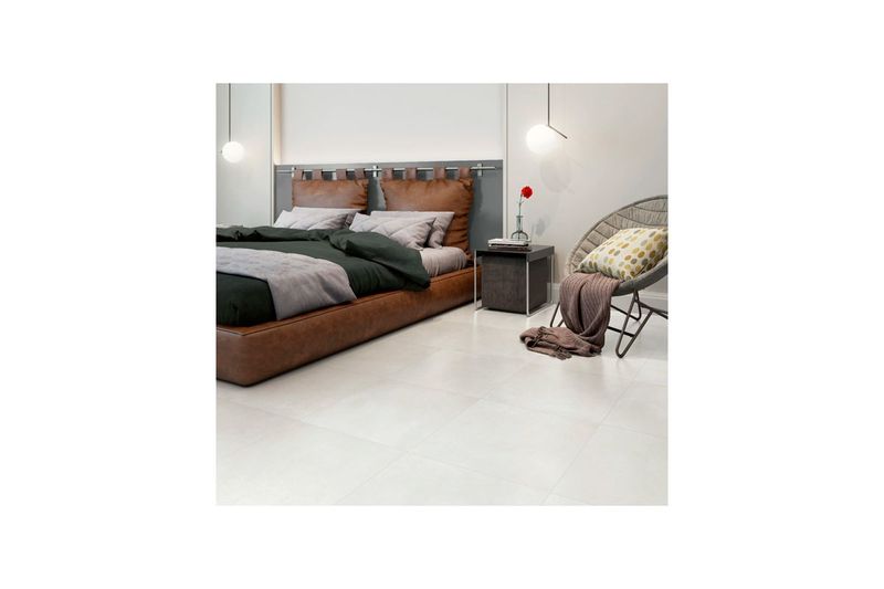 Baldosa 45x45 Grimes HD gris esfumado satinado Fioranno, instalada en el piso de una habitación con cama y silla