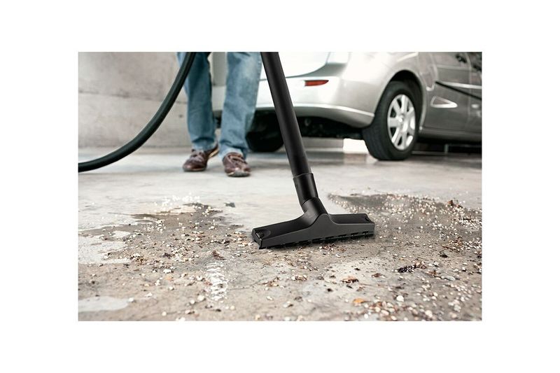 Aspiradora doméstica WD1 120V Kärcher 3.17 gal 1200W, boquilla de succión aspirando suciedad en el suelo junto a un auto
