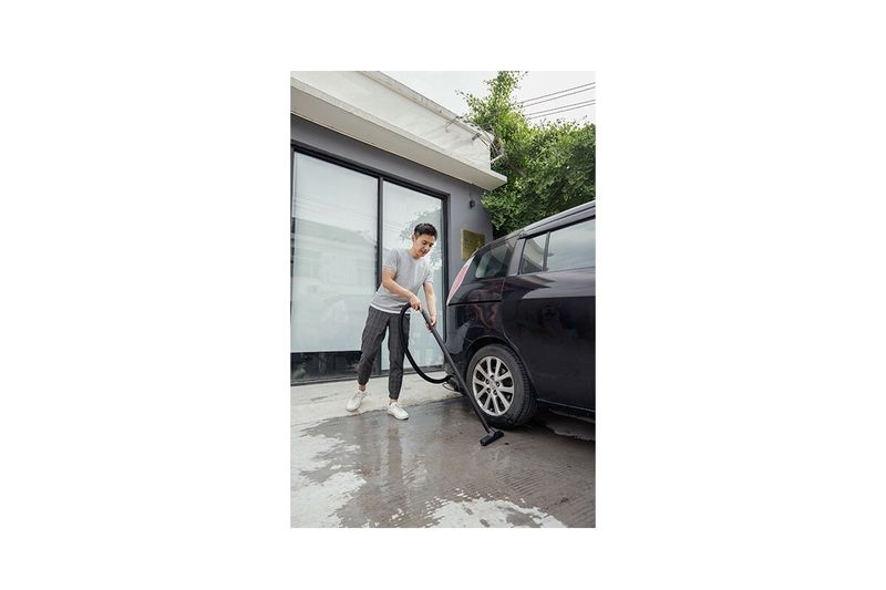 Aspiradora doméstica WD1 120V Kärcher 3.17 gal 1200W, hombre utilizándola para limpiar el piso junto a un auto negro
