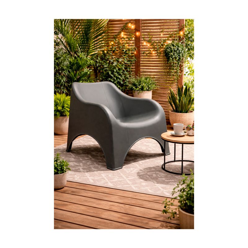 Silla individual verde Nuvola Koopman, ambientada en terraza de madera con plantas y mesa lateral pequeña