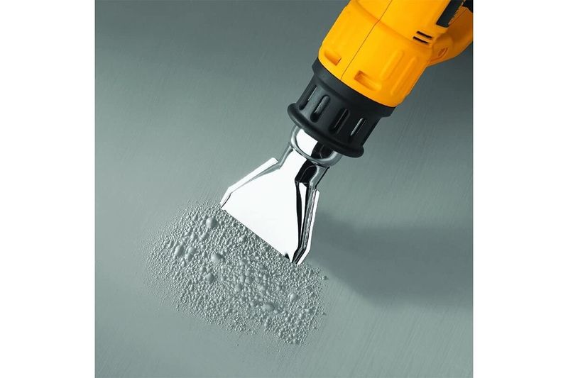 Pistola de calor DeWALT de 1550 watts y 110V, detalle de boquilla metálica eliminando pintura de una superficie
