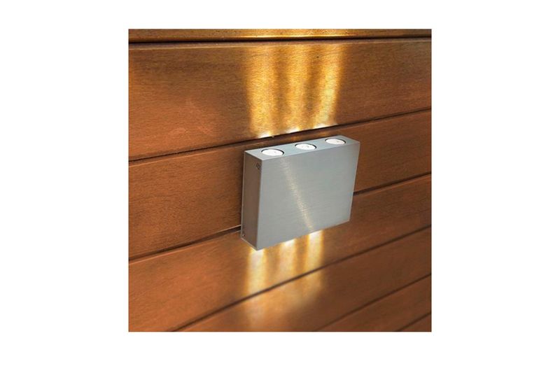 Luminaria de sobreponer al exterior LED Colina I 6 W 3000 K IP44 plateada Tecnolite, instalada en pared de madera encendida