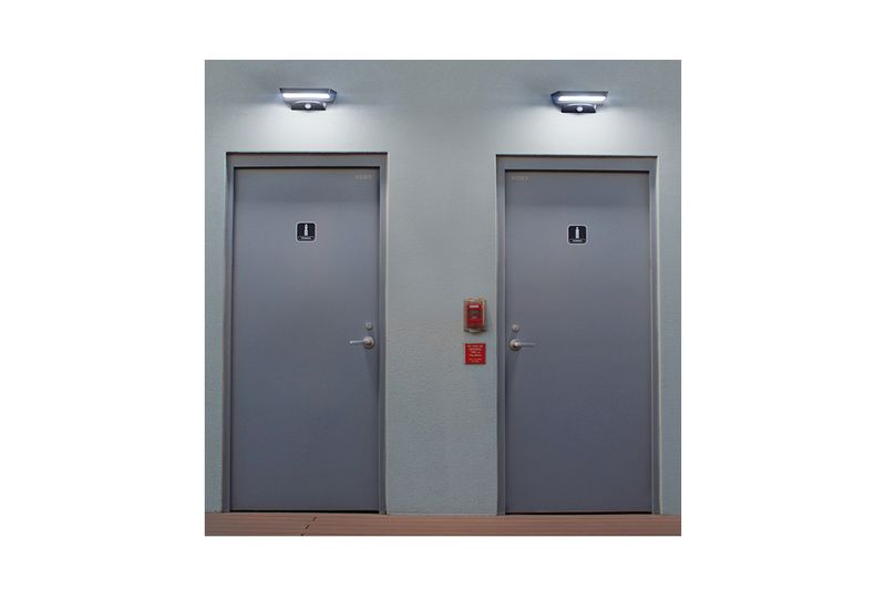 Arbotante solar de pared exterior con sensor LED 6500K 120-220V IP45 negro Volteck, instalado sobre dos puertas grises