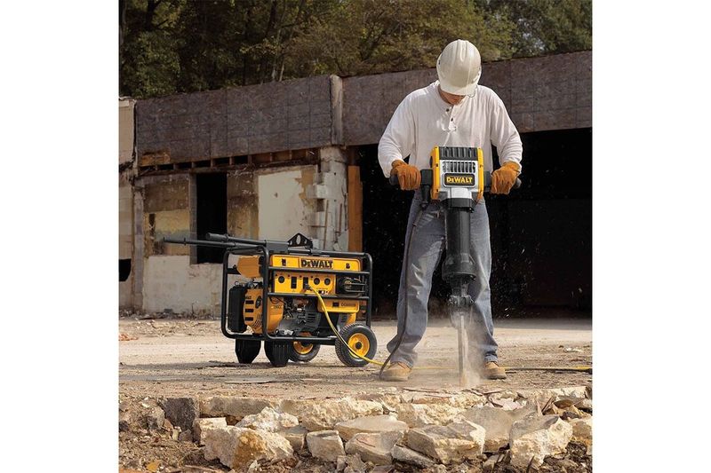 Rompepavimento hexagonal DeWALT de 1-1/8 pulgadas y 30 kg, en uso rompiendo concreto conectado a un compresor amarillo