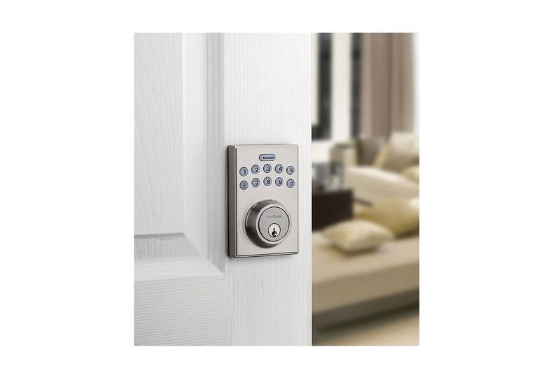 Cerradura digital 10 dígitos ovalada bronce veneciano Kwikset, instalada en puerta blanca con teclado numérico visible